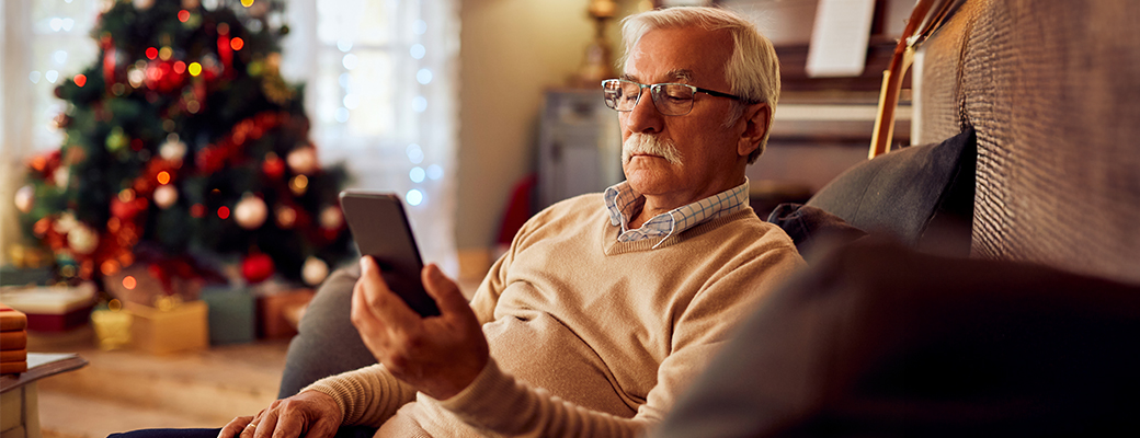 Image of senior man looking at his phone in his festive living room